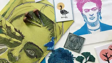 Works of art and printing tools arranged on a colorful table.