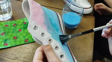 Schuh wird mit Pinsel und blauer Farbe bemalt.