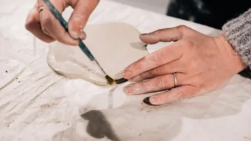 Hände formen, glätten und bemalen lehmartige Masse auf Tisch.
