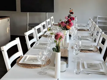 Long table with floral arrangements, setting for a meal.