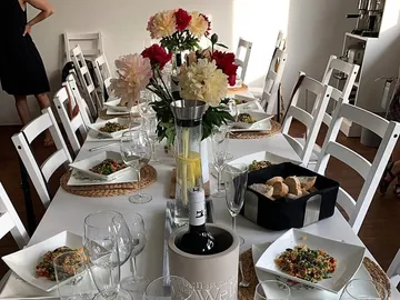 Tisch gedeckt mit Gerichten, Blumen und Getränken.