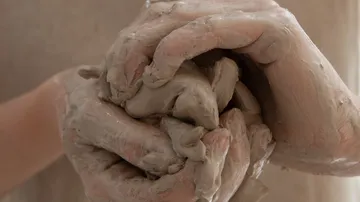 Hände formen feuchte Tonmasse im kreativen Atelier.
