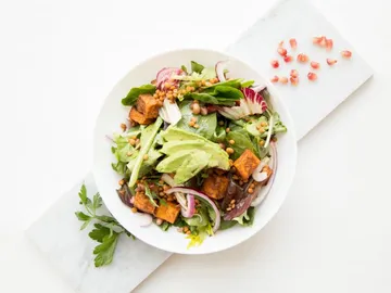Salad with vegetables, quinoa and avocado in a bowl.