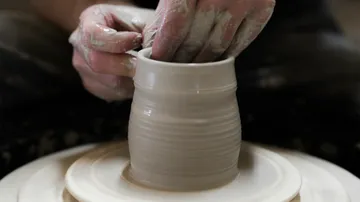 Clay jug is formed on a potter's wheel.