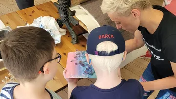 Zwei Kinder betrachten ein Buch, während eine Erwachsene erklärt.