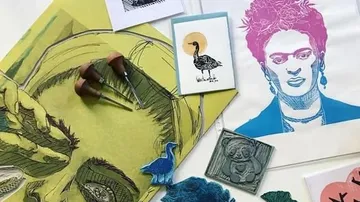Vielfältige Kunstwerke und Materialien liegen auf einem Tisch.