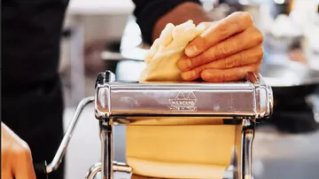 Pasta machine processes dough in a modern kitchen.