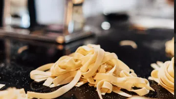 Fettuccine lies messy on a dark table surface.