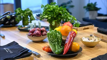 Fresh vegetables and fruit are laid out on a wooden table.
