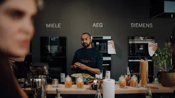 Koch steht hinter einer Theke und bereitet Zutaten vor.