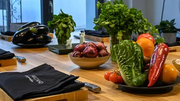 Fresh vegetables and herbs arranged on a wooden table.