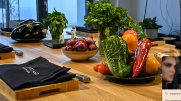Colourful vegetables and herbs lie on a wooden table.