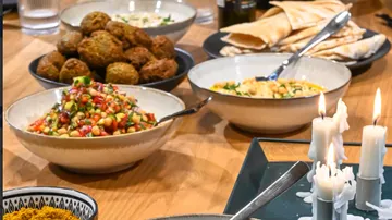 Various dishes are on a table with candlelight.