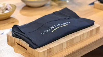 The apron lies neatly on a wooden board in a kitchen.