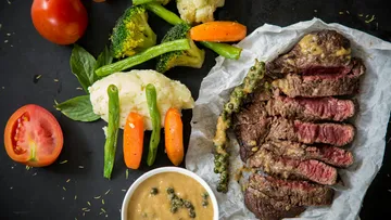 Grilled steak with vegetables and sauce on a plate.