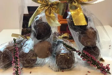 Wrapped chocolates with golden ribbons on a table.