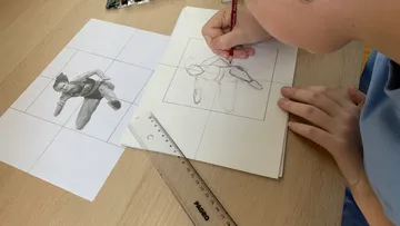Junge zeichnet anhand eines Bildes auf Papier.