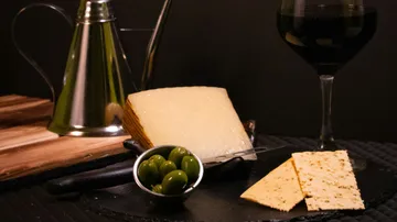 Cheese, olives and crackers with wine on black background.