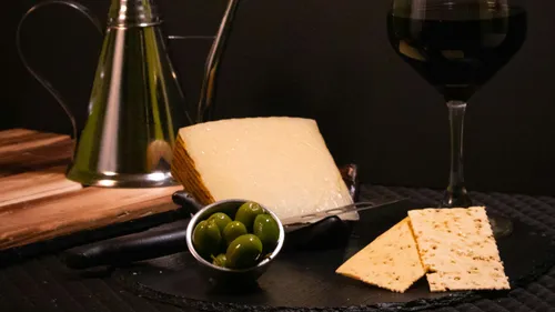 Cheese, olives and wine served on a table.