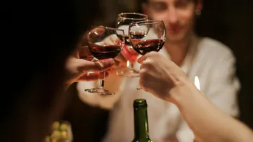 Glasses of red wine are held when toasted.