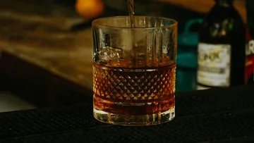 A glass is filled with a drink on a counter.