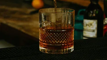 Ein Glas wird mit einem dunklen Getränk gefüllt.