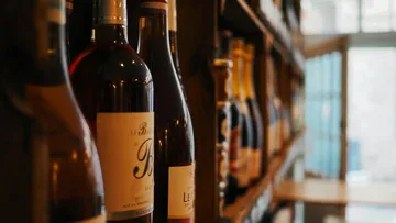 Wine bottles are on a shelf in a café.