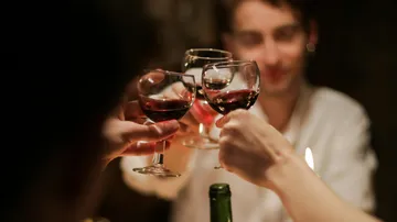 Glasses touch while people party in dim lighting.