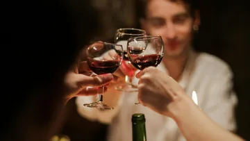 Glasses toast while people party in a convivial setting.