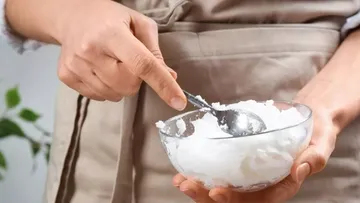 Eine Hand hält einen Löffel in einer Schüssel mit Sahne.