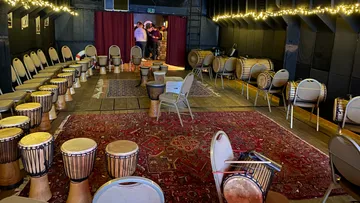 Round drums stand in a cozy room with chairs.