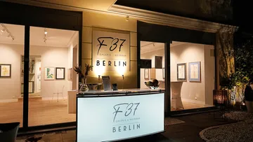 Galerie mit beleuchtetem Empfang und Kunstwerken in Berlin.