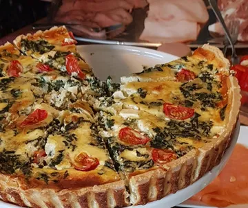 Quiche mit Tomaten und Spinat serviert auf einem Teller.