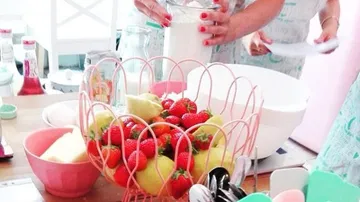 Früchte in einer Schüssel, während jemand Milch eingießt.