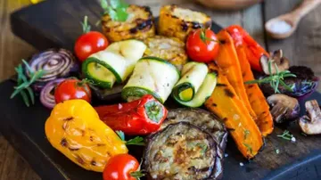 Grilled vegetables on wooden board, colourfully and deliciously arranged.