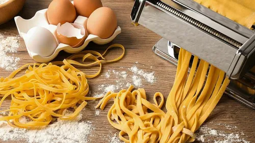 Nudeln werden mit einer Maschine auf einer Holzoberfläche hergestellt.