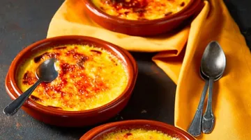 Drei Schalen Crème Brûlée liegen auf einem Tuch.