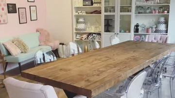 A wooden table is in a bright room with an armchair.
