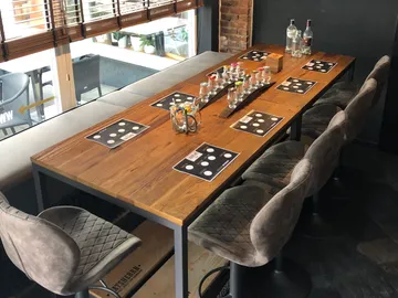 Wooden table with lots of glasses and seats in a restaurant.