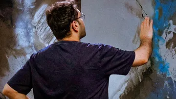 Man paints a patterned wall in an interior.
