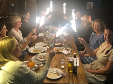 People celebrate with sparklers at a table full of food.