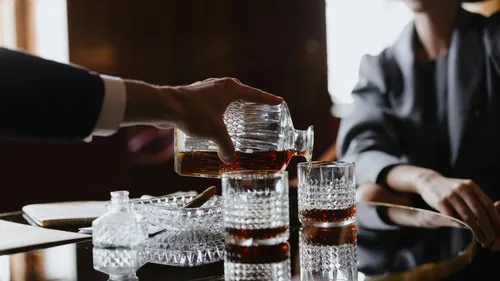 Mann schenkt Whisky in elegante Kristallgläser ein.