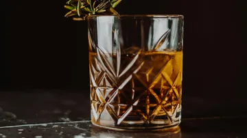 A glass of drink is on a dark table.