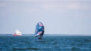 Windsurfer gleitet über das Wasser in ruhiger Umgebung.