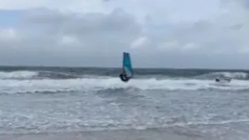 Surfer jumps over the waves in the ocean with a windsurfing board.
