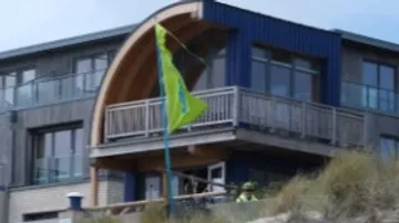 Helles Gebäude mit Balkon und wehendem gelben Flagge.