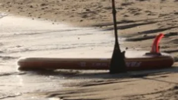 Stand-Up-Paddle-Board liegt im flachen Wasser am Strand.