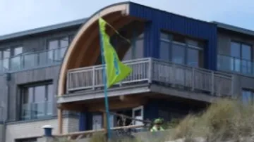 Ein Gebäude mit Balkon, eine Fahne weht im Wind.