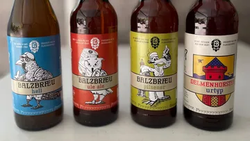 Four beer bottles with different labels stand next to each other.