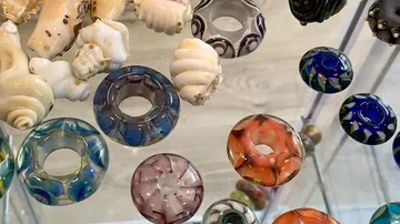 Colourful glass beads lie on a transparent surface.